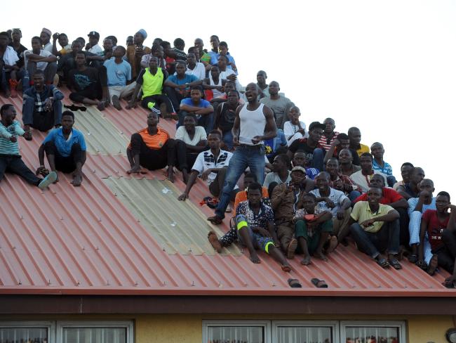 Supporters sit on the roof of a house to get a view of the pitch.Source:AFP