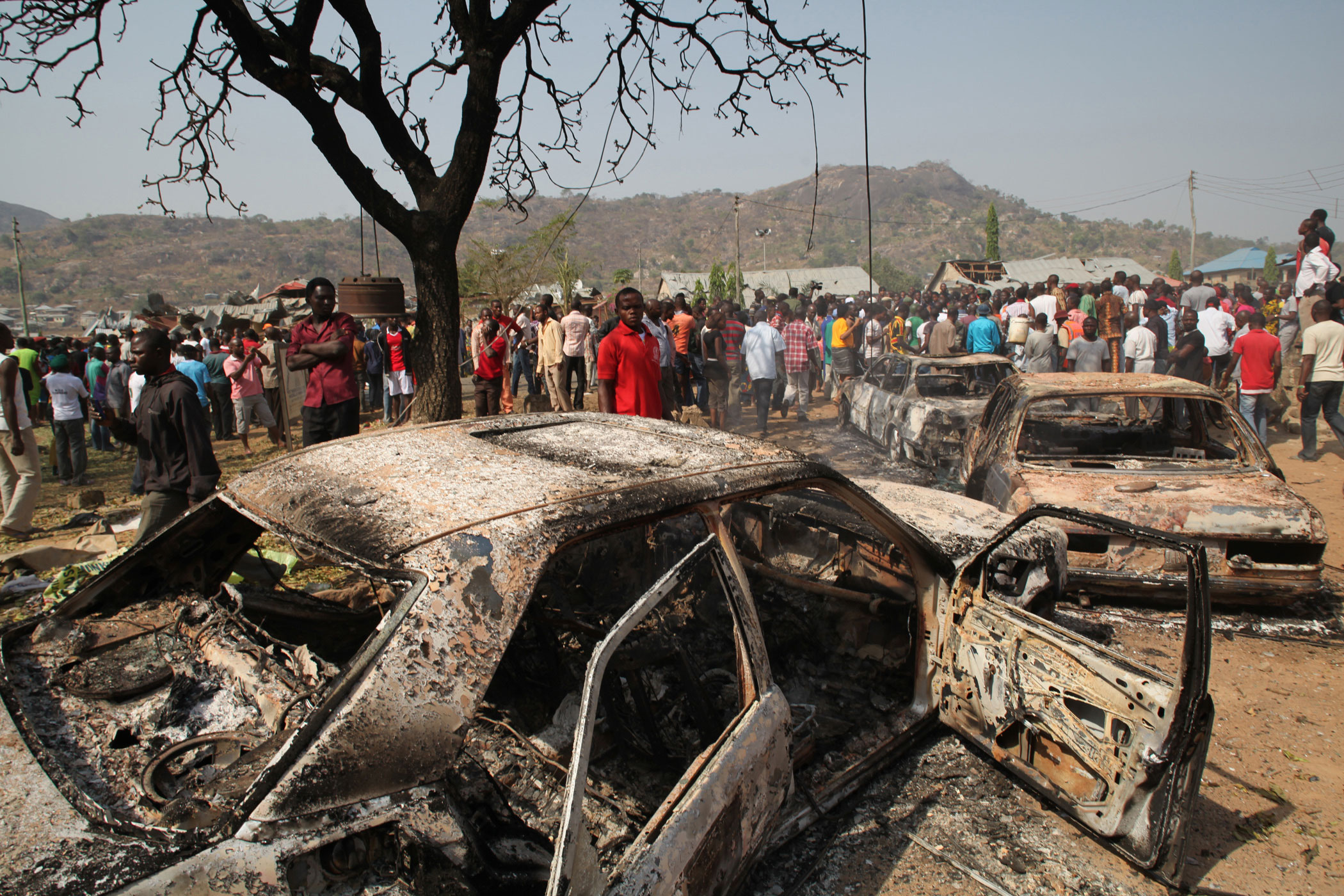 People gather around burnt cars near a Catholic church after a bomb blast in Nigeria’s capital, Abuja, on December 25, 2011. (Sunday Aghaeze/Getty Images)