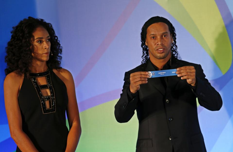 Brazil's soccer player Ronaldinho holds a paper that reads "Honduras," as he's flanked by former soccer player Aline Pellegrino during the draw for the men's Olympic football tournament in Rio de Janeiro, Brazil, Thursday, April 14, 2016. (AP Photo/Silvia Izquierdo)