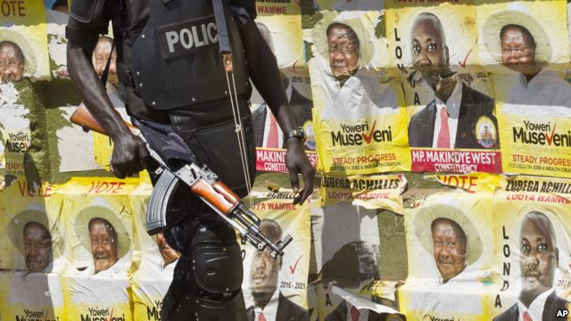 FILE - An armed Ugandan riot policeman is seen on patrol against the backdrop of campaign posters for long-time President Yoweri Museveni, as well as local members of Parliament, on a street in Kampala, Uganda, Feb. 17, 2016.