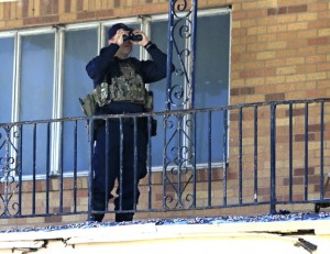 A police officer uses binoculars across from the Muhammad Mosque to monitor the situation. (Jae S. Lee/Staff Photographer