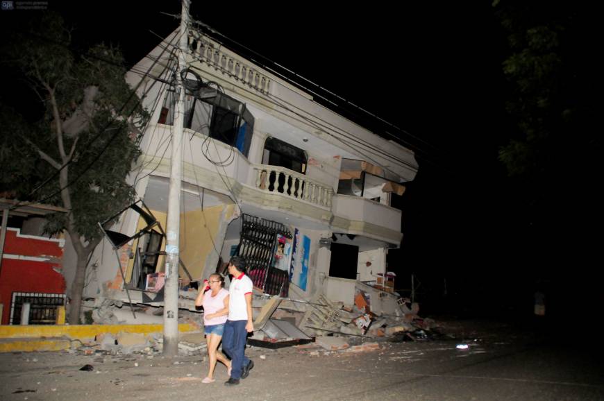 Residents walk on a street amid destroyed buildings following an earthquake Saturday in Guayaquil, Ecuador. | AFP-JIJI