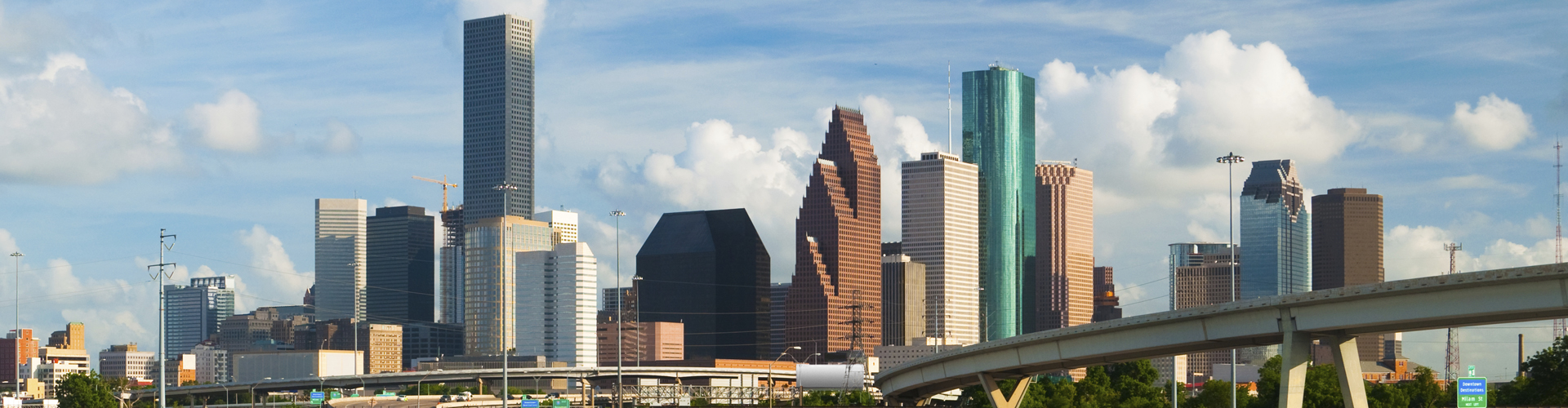 Houston downtown skyline with beautiful clouds in the background and Interstate 10 freeway and Whiteoak bayou in the foreground.