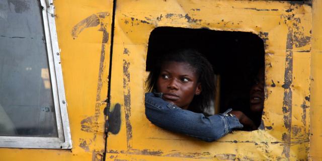 Commuters peer from a broken window on a public bus in Lagos, March 27, 2009. Nigeria continues to suffer from numerous economic headaches including lower oil prices and the government's controversial foreign-exchange and price-control policies (which analysts have more or less deemed a failure.)