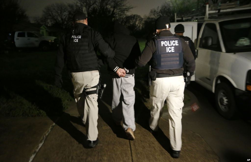 FILE - U.S. Immigration and Customs Enforcement agents escort a handcuffed undocumented immigrant convicted of a felony that was taken into custody during an early morning operation in Dallas.