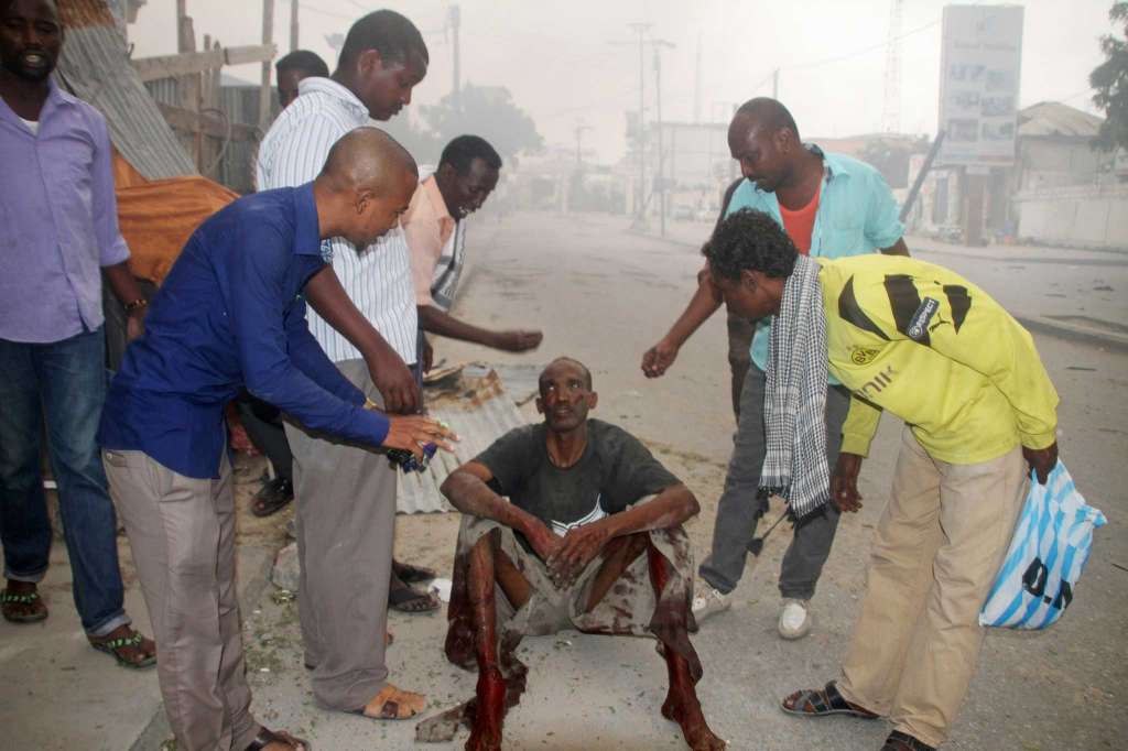 Somali men help a civilian who was wounded in a suicide car bomb attack on a hotel in Mogadishu, Somalia, Saturday, June 25, 2016. A Somali police officer says a suicide car bomber detonated an explosives-laden vehicle at the gate of a hotel in Mogadishu followed by gunmen who were fighting their way into the hotel..