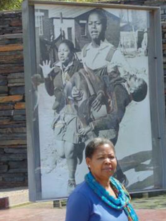 Antoinette Sithole in front of the iconic photo of herself reacting to the death of her brother, Hector Pieterson, 40 years ago in Soweto. (Photo: Bill Sternberg)