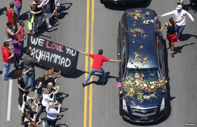 A well-wisher holding a banner touches hearse carrying remains of Muhammad Ali during funeral procession for the three-time heavyweight boxing champion in Louisville, Kentucky, June 10, 2016.