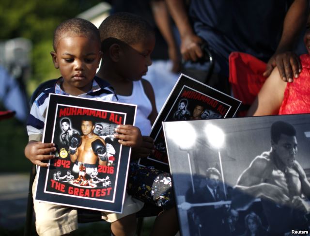 Brandon Liggons, 2, (L) holds an image of Muhammad Ali during the funeral procession for the three-time heavyweight boxing champion in Louisville, Kentucky, June 10, 2016.