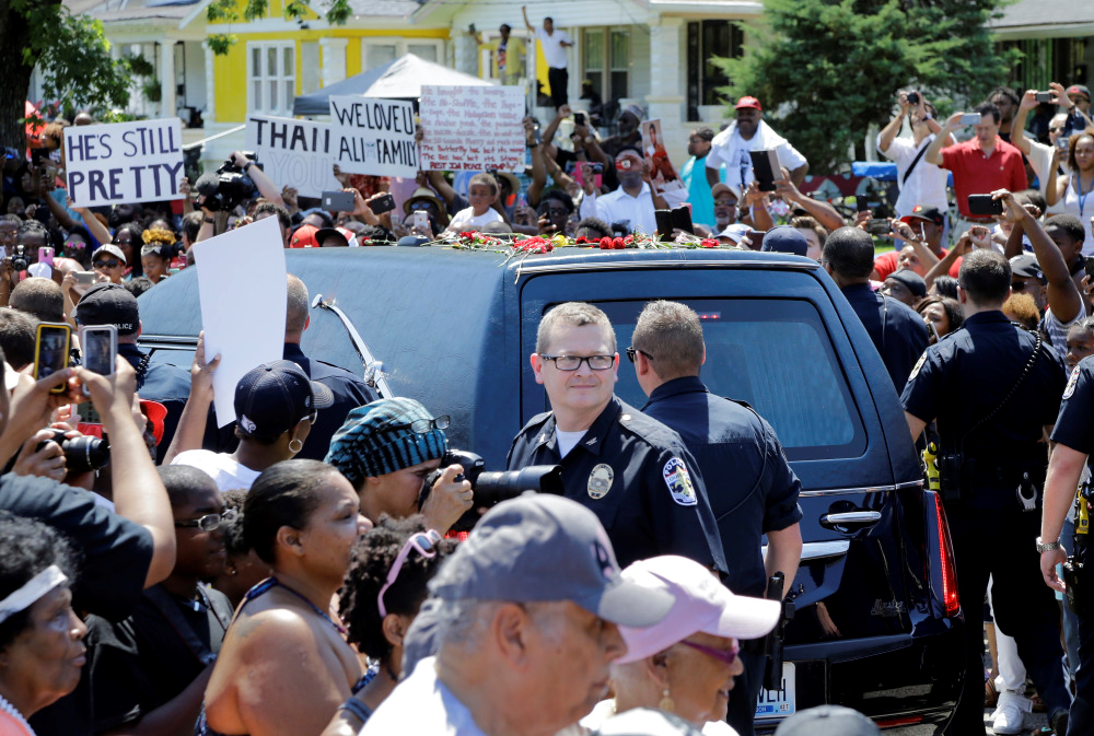 Police escort the hearse carrying the body of Muhammad Ali as it passes through the crowded