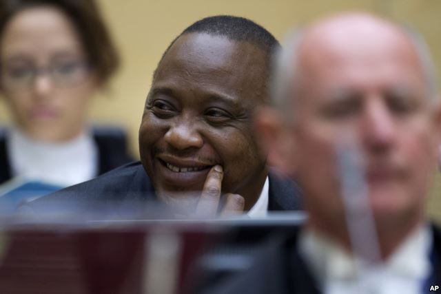 FILE - Kenya's president Uhuru Kenyatta smiles as he sits with his defense team when appearing before the International Criminal Court in The Hague, Netherlands, Wednesday Oct. 8, 2014.