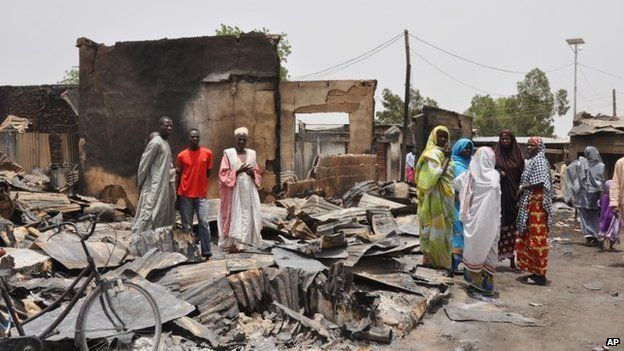 People stand outside burnt houses following an attack by Islamic militants in Gambaru, Nigeria 