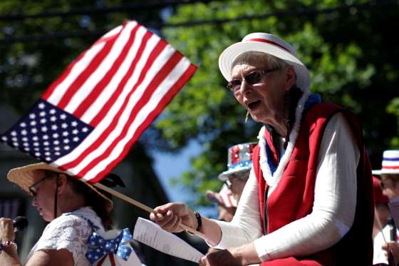 A woman sings while waving an American flag while riding a float through Barnstable Village in Barnstable, Massachusetts.
