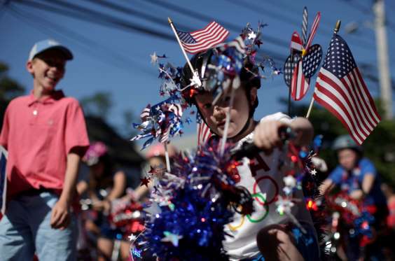 A boy wears decorations as he rides his bicycle through Barnstable Village in Barnstable, Massachusetts.