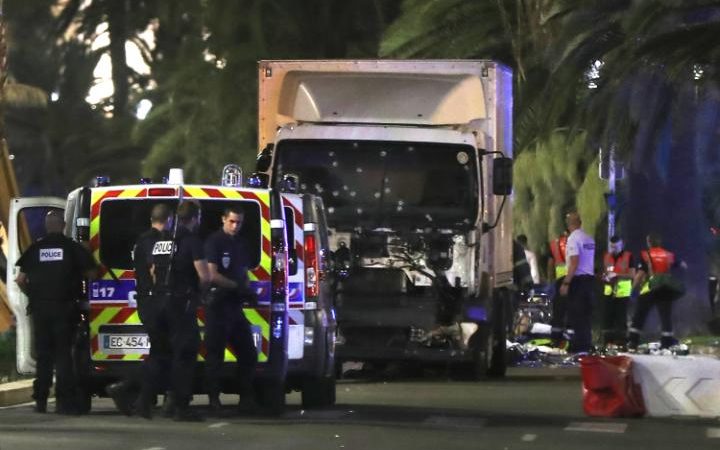 Police officers and rescued workers stand near a van that ploughed into a crowd in Nice