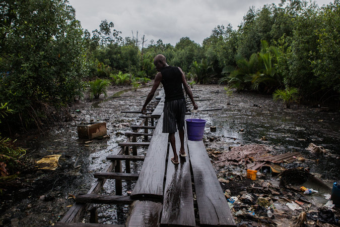 A man walked along the former jetty of Ugborodo, Nigeria. The water in the area is heavily polluted by oil. 