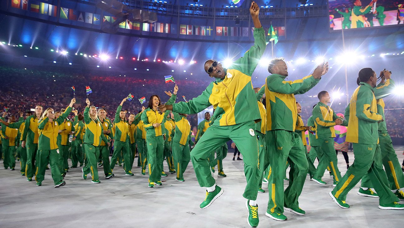 Members of the South African team wave their country's flag as they enter the stadium