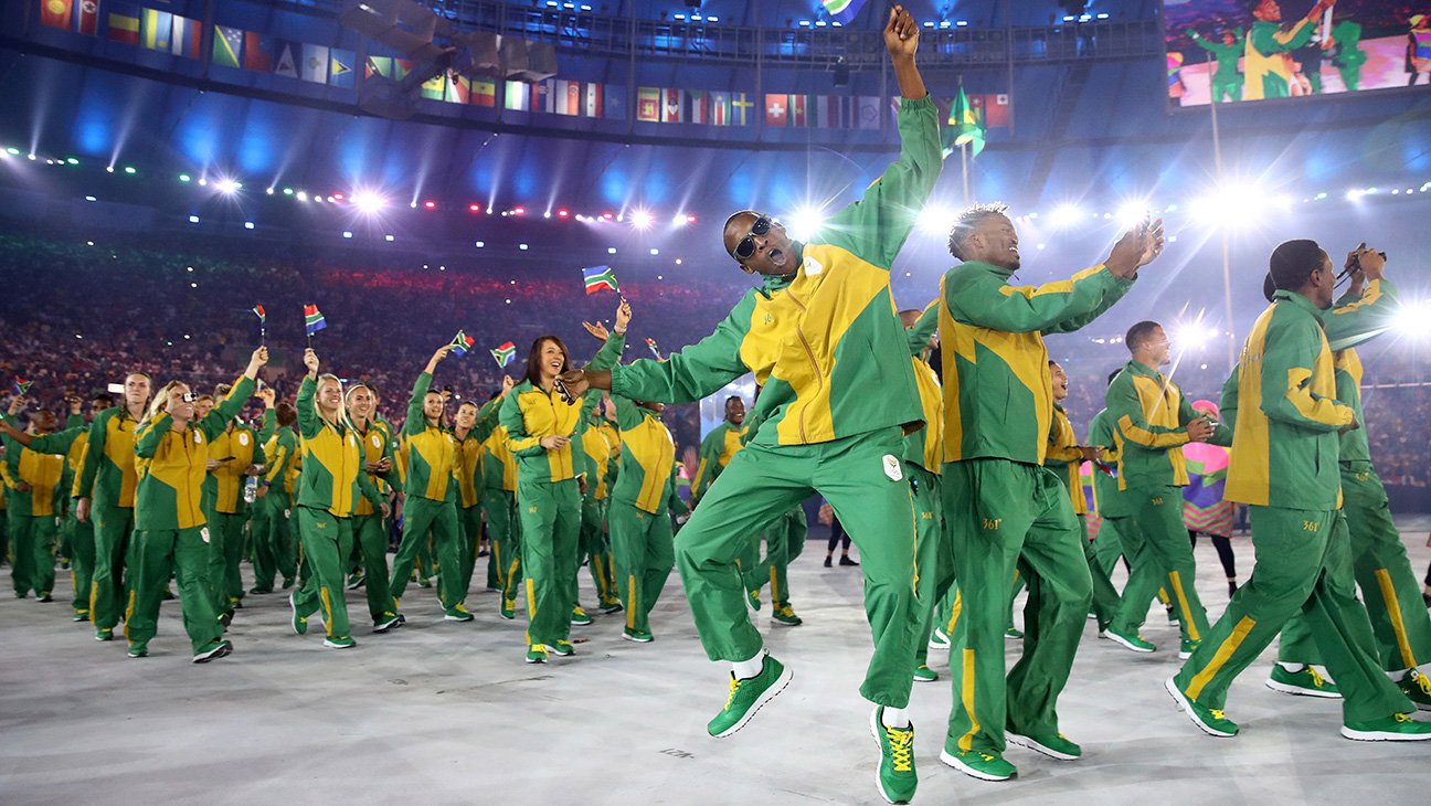 Members of the South African team wave their country's flag as they enter the stadium