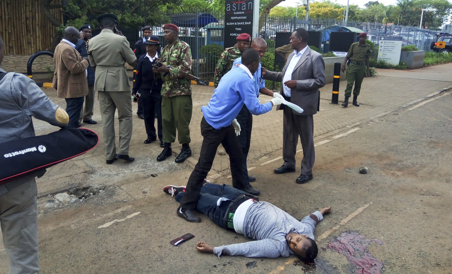 Kenyan security forces stand next to the body of a man who was killed outside the U.S. Embassy in Nairobi, Kenya Thursday, Oct. 27, 2016. A Kenyan police official said the man was shot dead after stabbing a policeman guarding the perimeter wall of the U.S. Embassy in Nairobi. (Associated Press) 